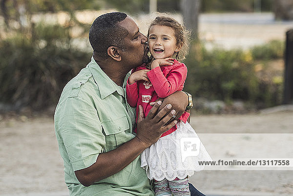 Vater küsst Tochter auf Spielplatz