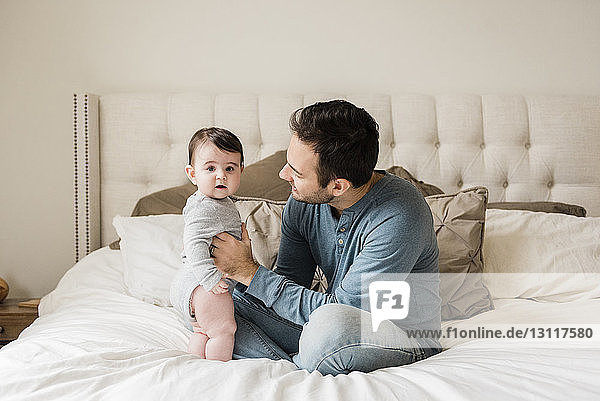 Portrait of cute son with father on bed at home