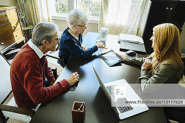 High angle view of financial advisor explaining plan to senior couple on tablet computer in office
