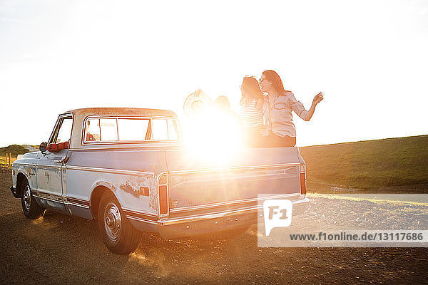 Friends travelling in pick-up truck during sunset