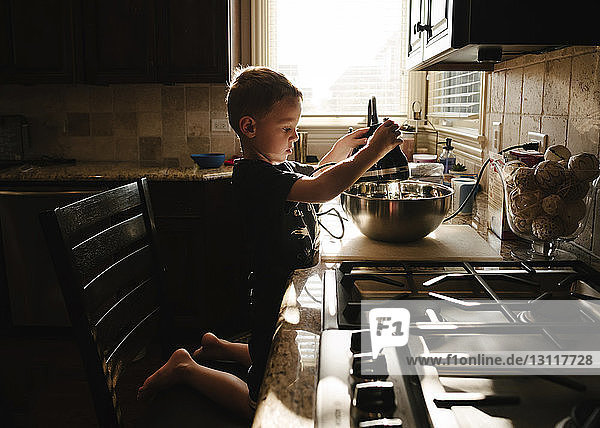Seitenansicht eines Jungen  der zu Hause in der Küche Essen zubereitet