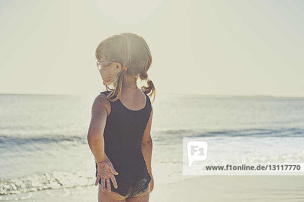 Rückansicht eines am Strand stehenden Mädchens in Badebekleidung