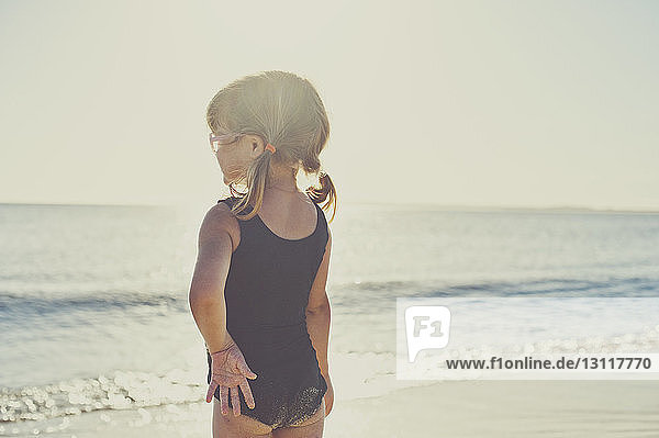 Rear view of girl in swimwear standing on beach