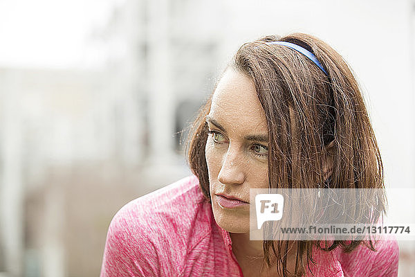 Close-up of tired thoughtful woman looking away while resting in park