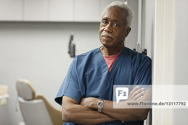 Portrait of doctor with arms crossed leaning on wall in hospital