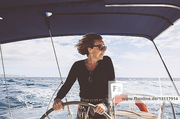 Reife Frau fährt Boot auf dem Meer gegen den Himmel