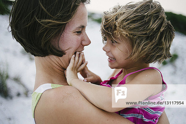 Seitenansicht einer Mutter mit glücklicher Tochter am Strand