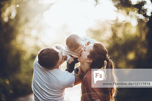 Father holding son biting mother's nose