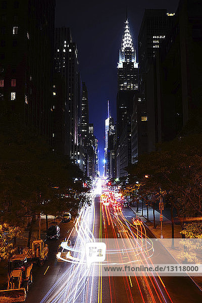 Lichtspuren auf Stadtstraßen durch beleuchtete Gebäude bei Nacht