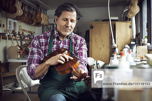 Worker touching violin while working in workshop