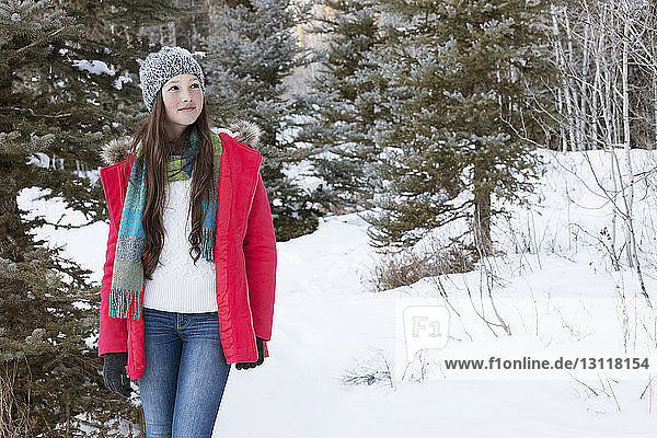 Girl looking away while standing on snowy field
