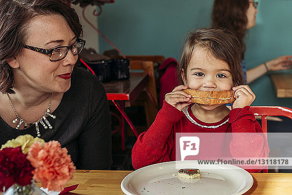 Mutter beobachtet Tochter beim Brotessen am Restauranttisch