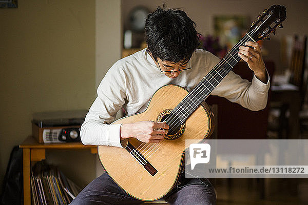 Mann spielt Gitarre  während er zu Hause sitzt