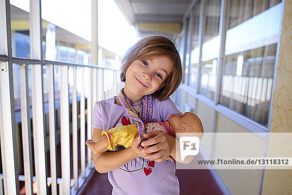 Porträt eines glücklichen Mädchens mit einer Puppe im Korridor