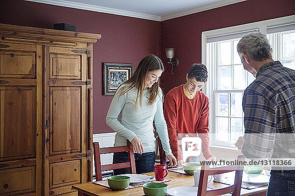 Lächelnde Familie deckt den Tisch zu Hause