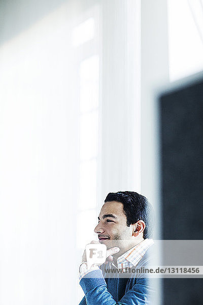 Side view of smiling businessman sitting at office