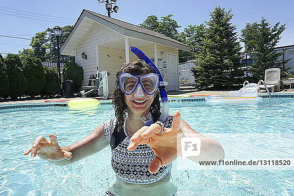 Porträt einer glücklichen Frau mit Schnorchel beim Schwimmen im Pool an einem sonnigen Tag