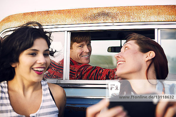Cheerful woman using mobile phone while traveling with friends