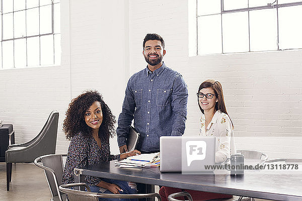 Portrait of confident smiling business people at table in office