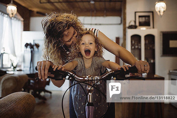 Mutter mit Tochter zu Hause Fahrrad fahren