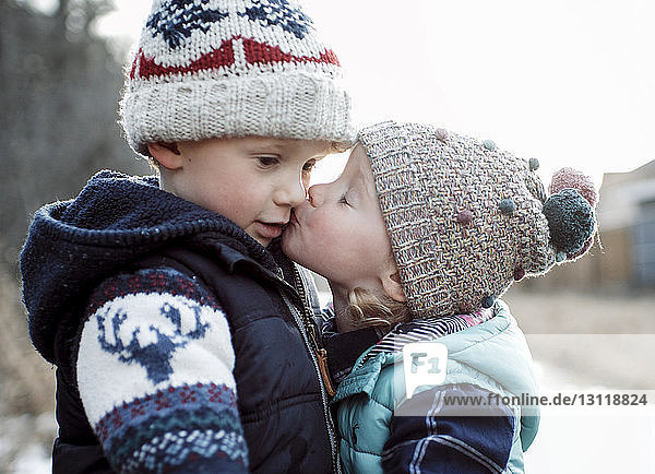Loving sister kissing brother during winter