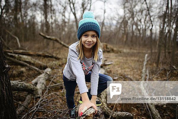 Portrait of confident girl leaning on dried branch at forest