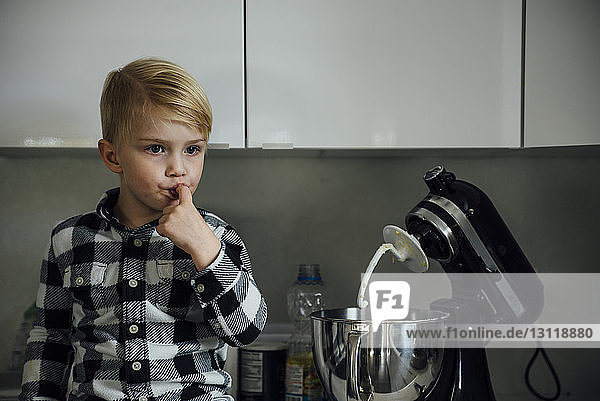 Süßer Junge probiert Essen aus dem Mixer in der Küche