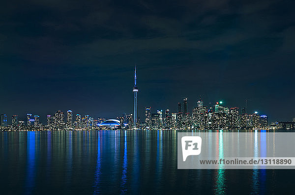 Beleuchtete moderne Gebäude  die sich im Ontariosee gegen den nächtlichen Himmel spiegeln