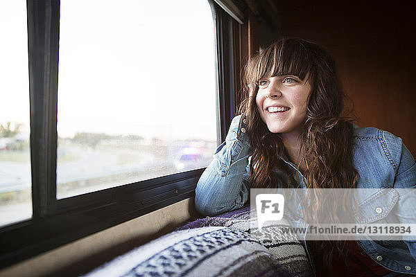 Frau lächelt  während sie im Wohnmobil am Fenster sitzt