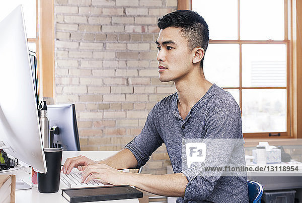 Geschäftsmann  der am Desktop-Computer im Büro arbeitet