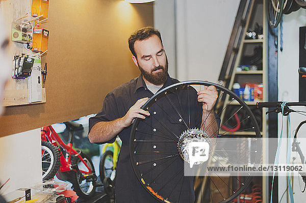 Männlicher Mechaniker repariert Fahrradreifen in Werkstatt