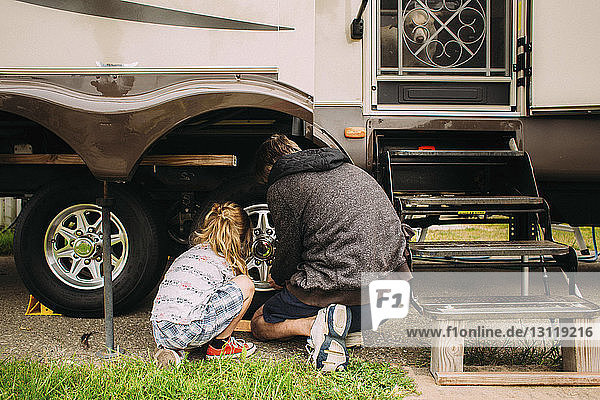 Rückansicht von Vater und Tochter bei der Reifenreparatur
