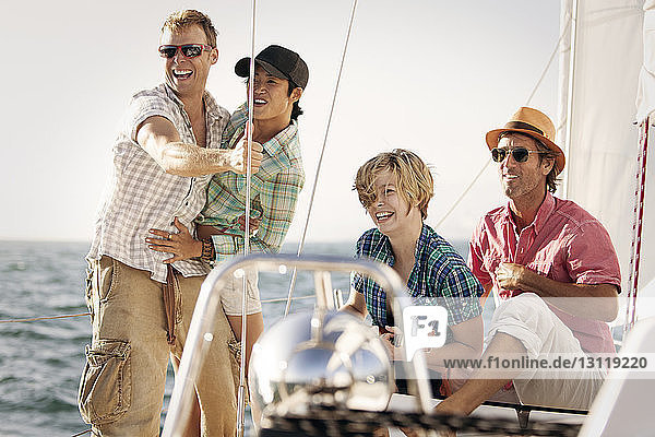 Happy friends enjoying on boat against sky