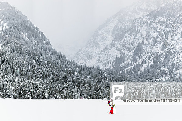 Seitenansicht einer Frau mit Rucksack beim Wandern auf schneebedecktem Feld