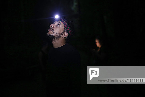 Mann schaut nachts mit Scheinwerfer auf