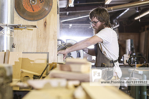 Carpenter using circular saw in workshop