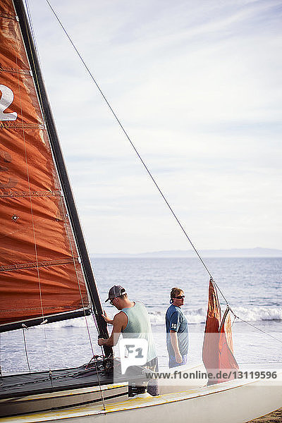 Mann baut ein Segelboot  während er mit seinem Vater am Strand steht