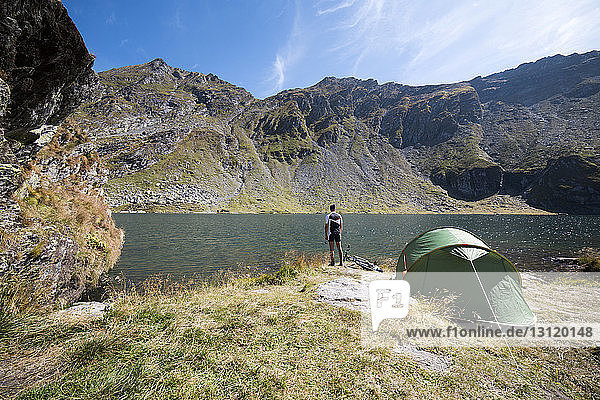 Rear view of man standing by tent against lake