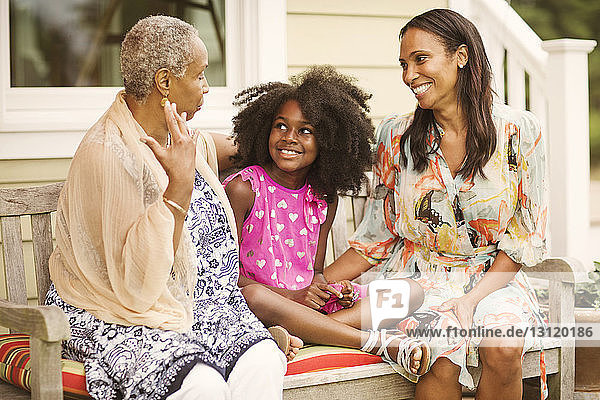 Mädchen sitzt mit Mutter und Großmutter auf der Bank im Innenhof