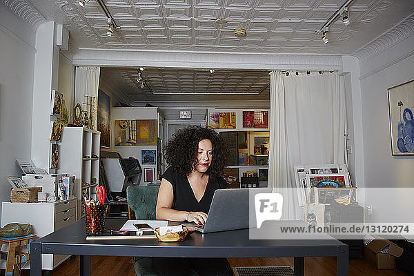 Weiblicher Besitzer benutzt Laptop-Computer am Tisch in der Galerie