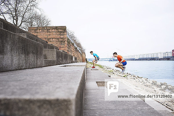 Side view of male athletes jumping on steps at beach