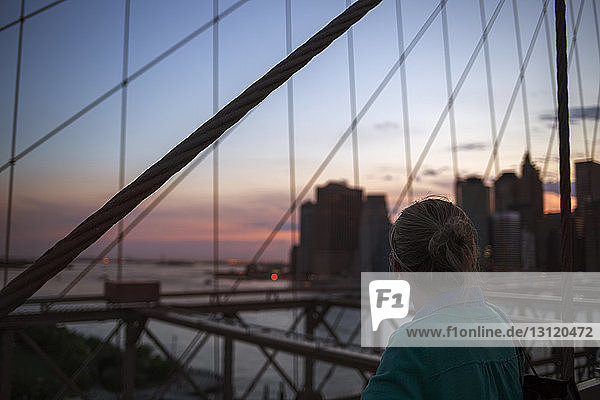 Rückansicht einer Frau auf der Brooklyn Bridge bei Sonnenuntergang