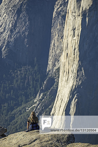 Frau sitzt bei Sonnenschein auf einer Klippe im Yosemite National Park