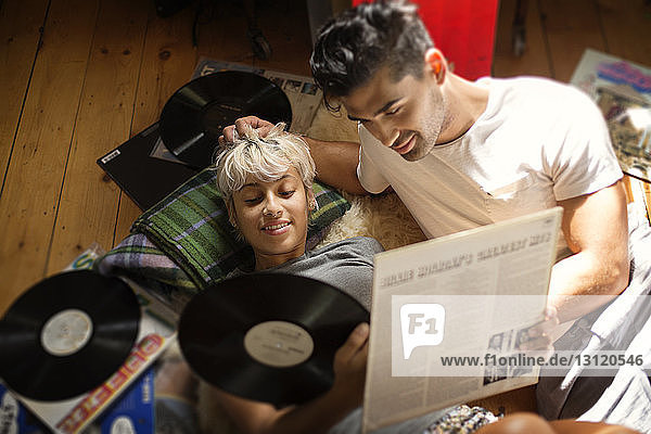 Overhead view of couple looking at vinyl records while lying on floor