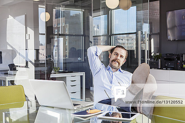 Relaxed businessman sitting with feet up on conference table in board room