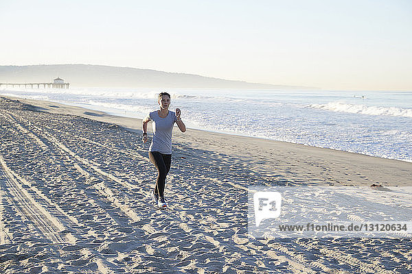 Frau in voller Länge am Strand joggend