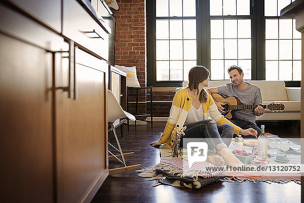 Man playing guitar for girlfriend at home