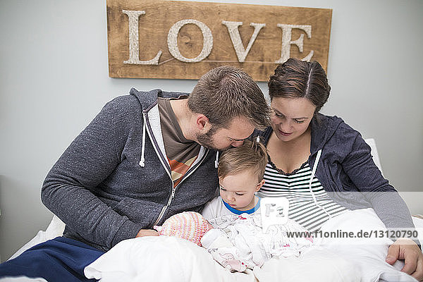 Liebevolle Eltern mit Sohn und neugeborener Tochter zu Hause im Bett sitzend