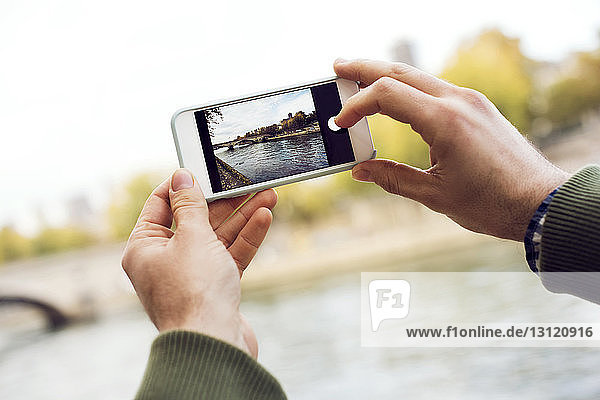 Ausgeschnittene Hände fotografieren Fluss durch Smartphone
