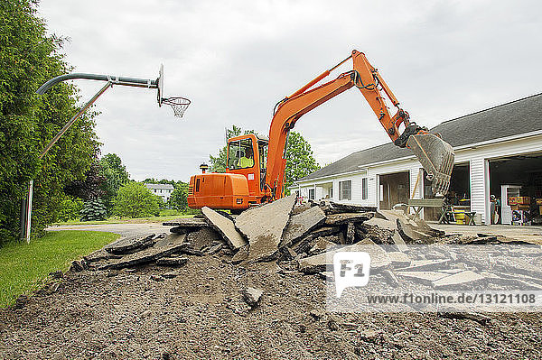 Mann in Erdbewegungsmaschine gräbt Land auf Baustelle